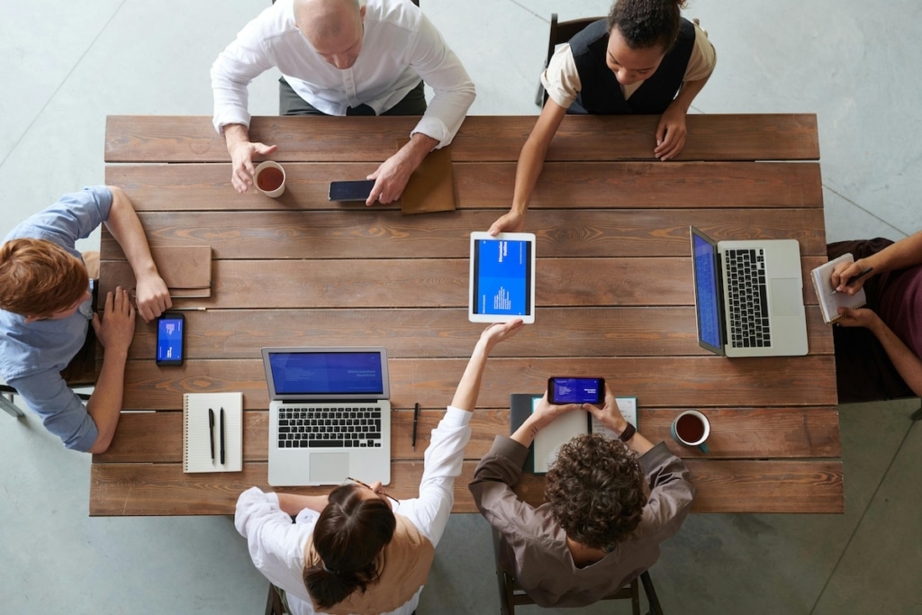 tafel waar mensen aan werken met laptops